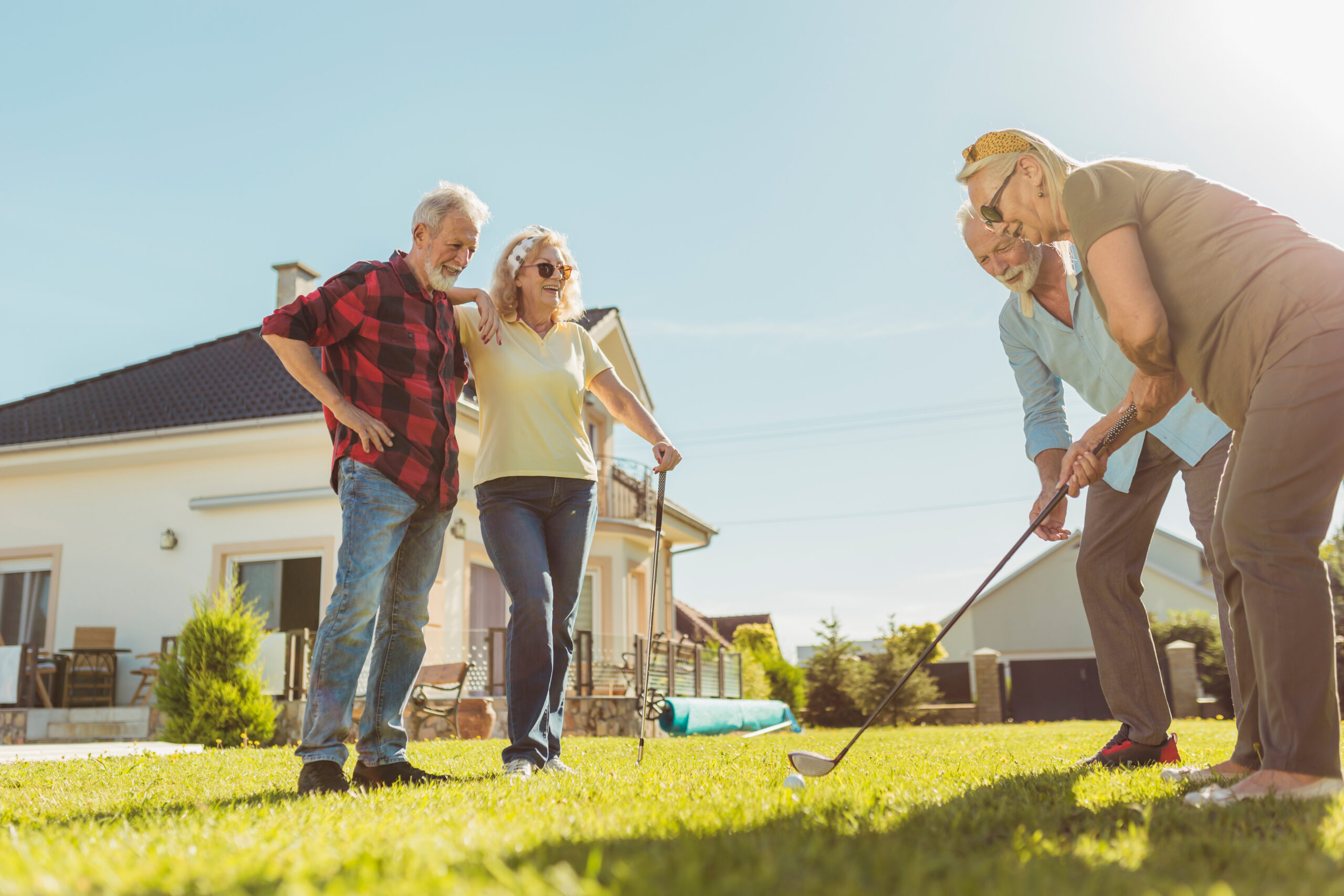 Senior friends playing mini golf in the backyard